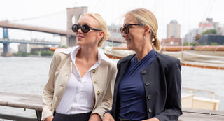 Two women standing on a bridge with a cityscape in the background