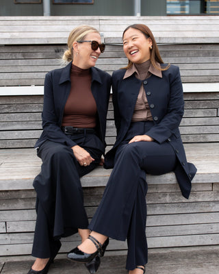 Two women sitting on a wooden bench wearing luxeire outfits.