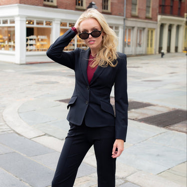 Woman in a black suit standing on a city street.