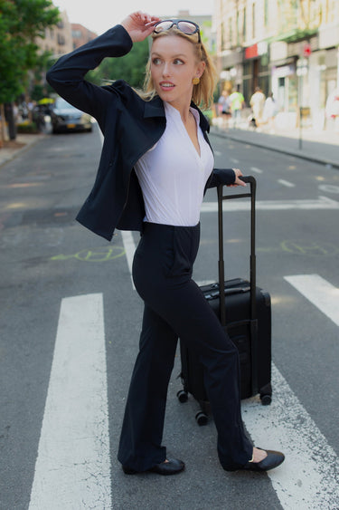 Woman in a suit with a suitcase crossing a street on a zebra crossing