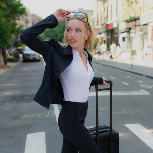 Woman in professional attire with a suitcase on a city street
