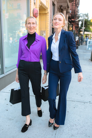 Two women in business attire walking on a city street.