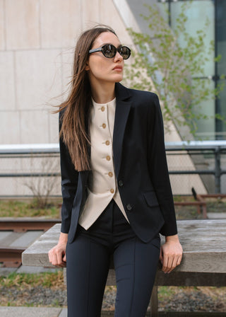 Woman in a professional outfit sitting on a bench outdoors.
