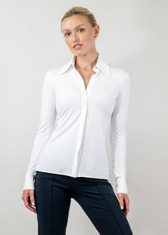 Woman wearing a white blouse and dark pants against a plain background