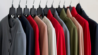 Row of colorful coats hanging on a rack against a white wall