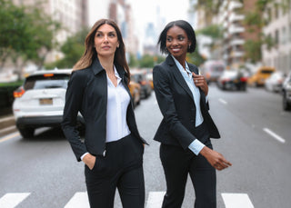 Two women in business attire walking on a city street.